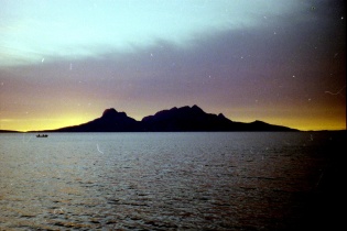 Soleil de minuit à Bodø derrière montagnes avec bateau